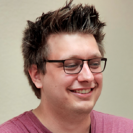 Corbin Crutchley smiling, wearing glasses and a pink shirt